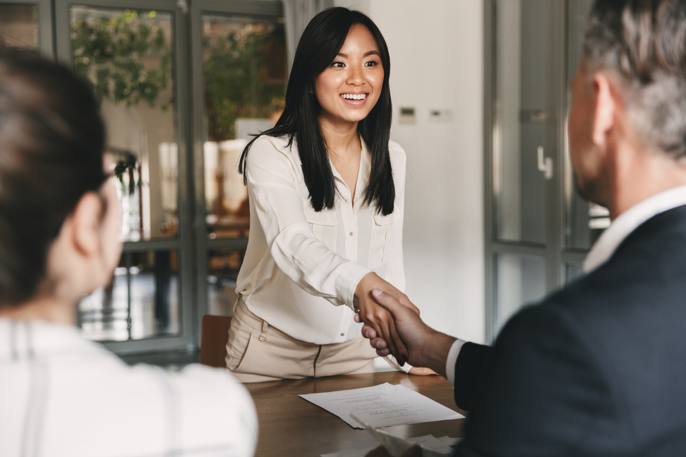 Joyful moment captured as a women and one man engage in a handshake during a business meeting. The woman's genuine smile adds a positive touch to the customer interaction.